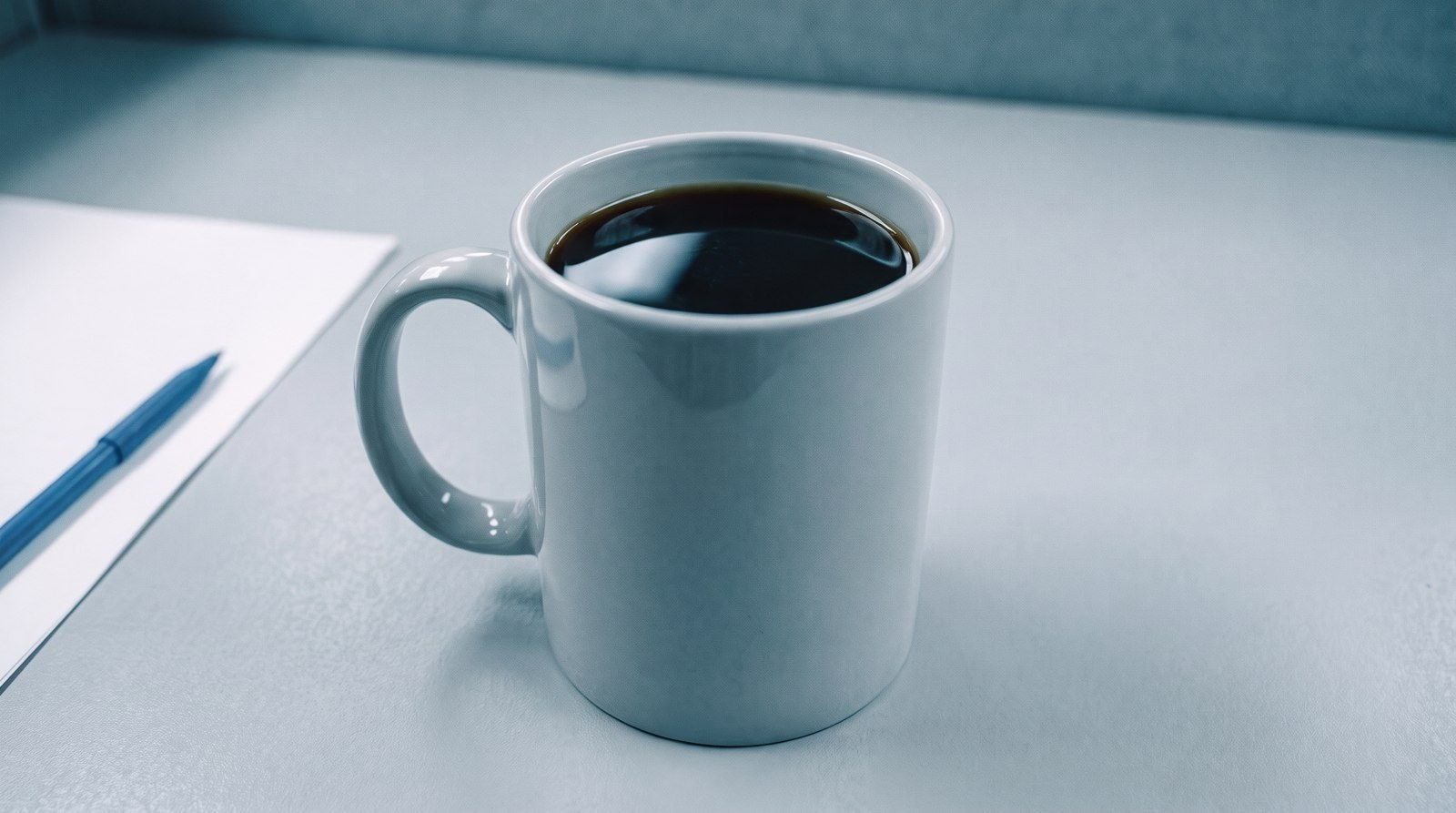 Taza gris con café negro sobre un escritorio
